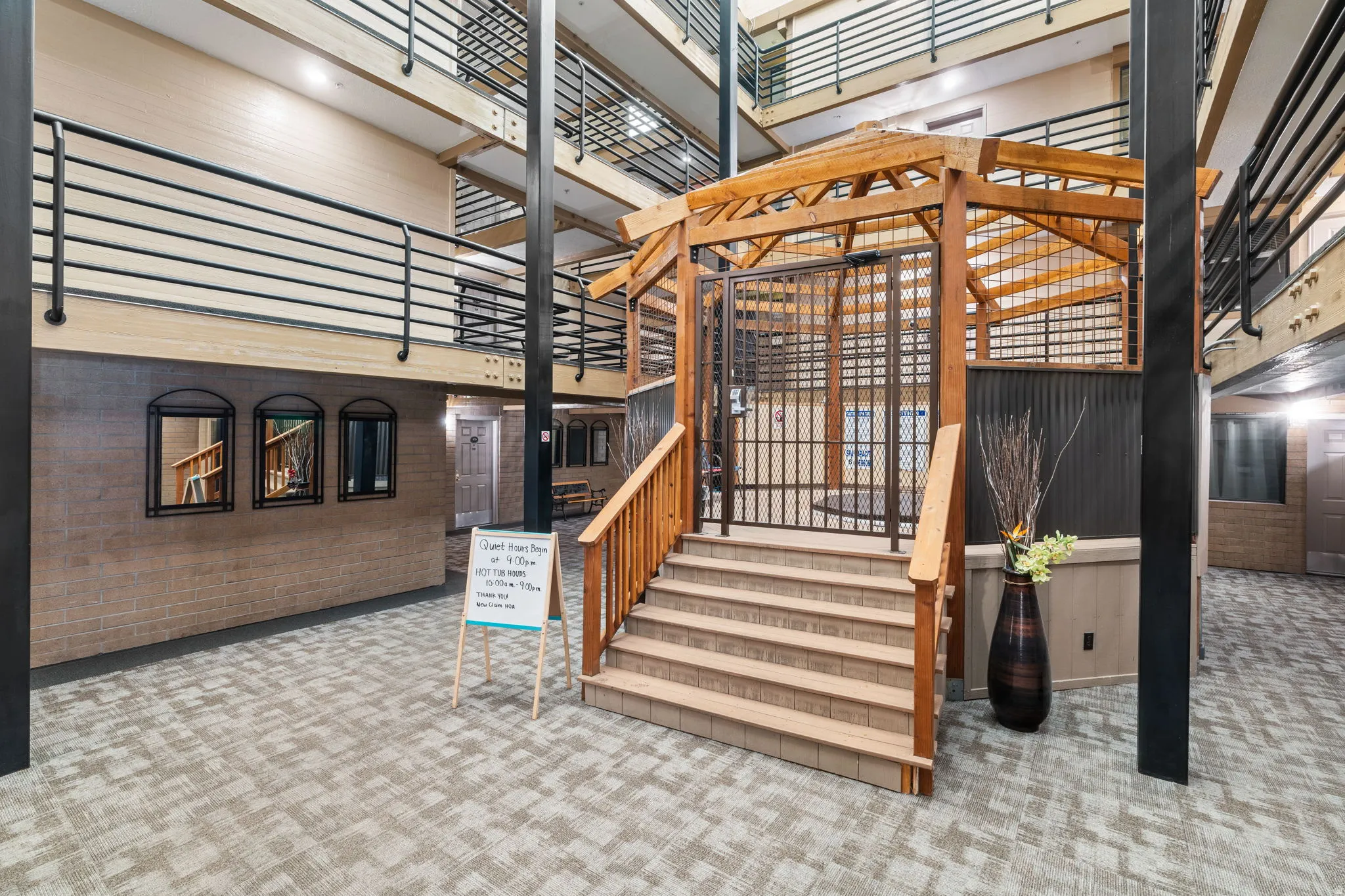 Open-air multi-story atrium featuring a wood-frame gazebo, exposed structural beams, and wrought iron railings