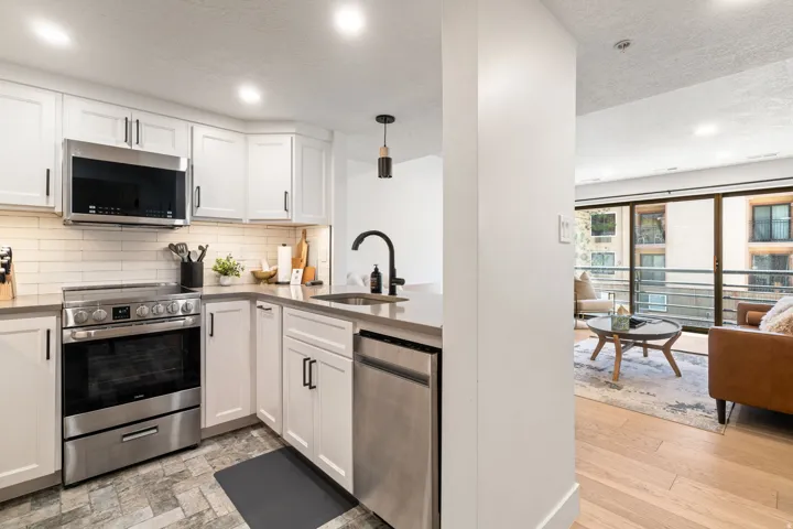 Kitchen featuring white shaker cabinetry, stainless steel appliances, light-toned countertops, and a subway tile backsplash
