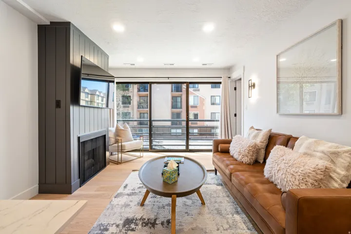 Living area featuring wood-finish flooring, a full wall of glass doors opening to a balcony, and recessed lighting