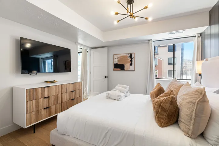 Spacious room featuring a large window, light wood-finish flooring, and a modern chandelier
