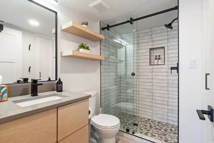 Contemporary bathroom featuring a floating wood-finish vanity with an integrated rectangular sink and a dark countertop