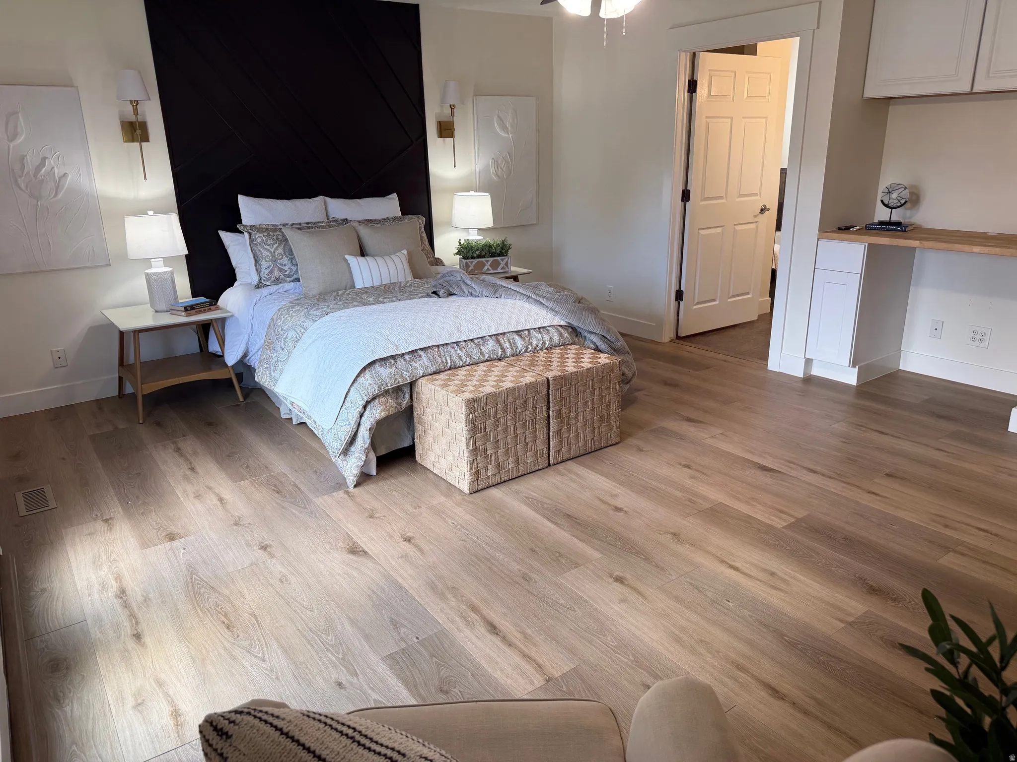 Spacious room featuring wood-finish flooring, a dark accent wall with decorative paneling, and built-in desk cabinetry with a light wood countertop