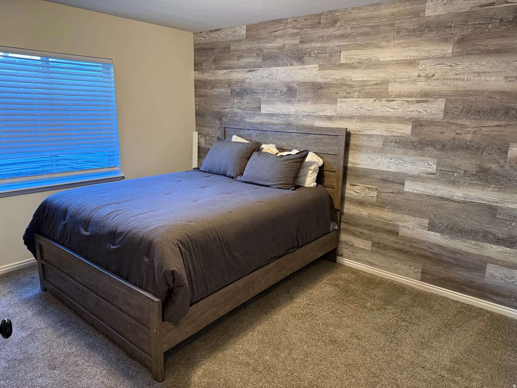 Interior space featuring a wood-look accent wall, neutral painted walls, and carpet flooring