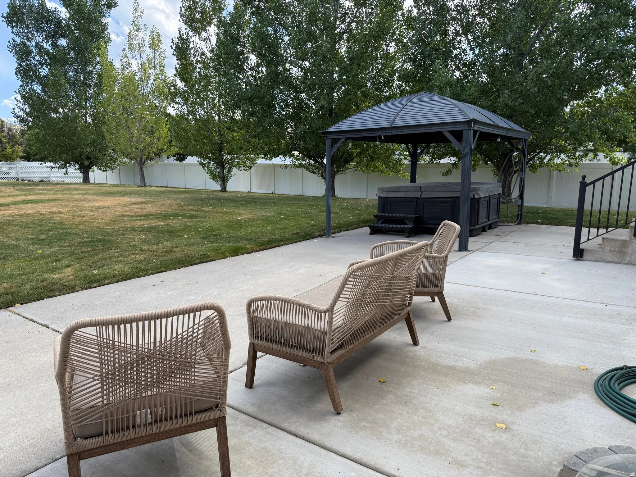 Concrete patio with a freestanding gazebo and an integrated spa