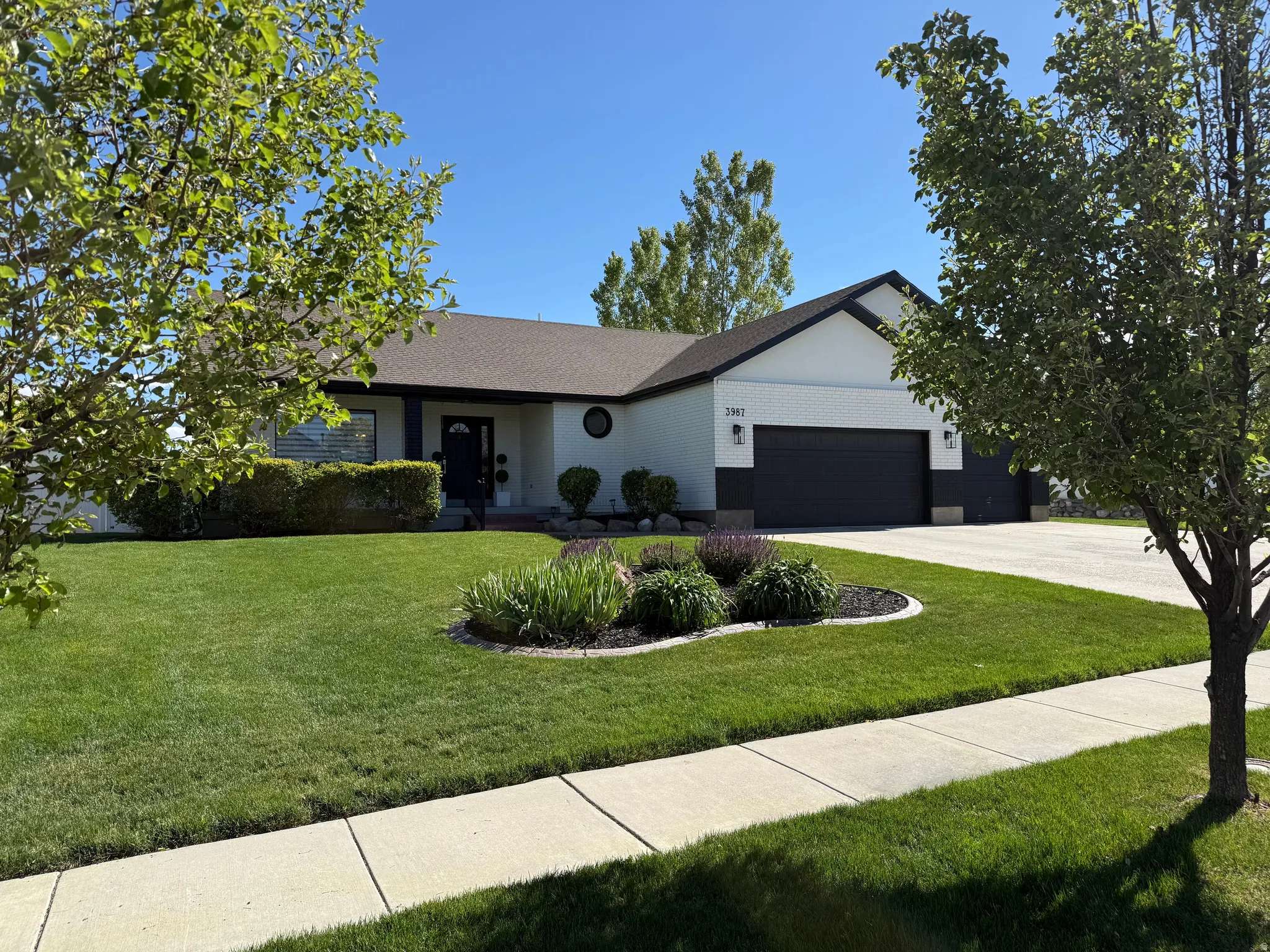 Contemporary ranch-style residence featuring a white exterior with dark trim and a two-car garage