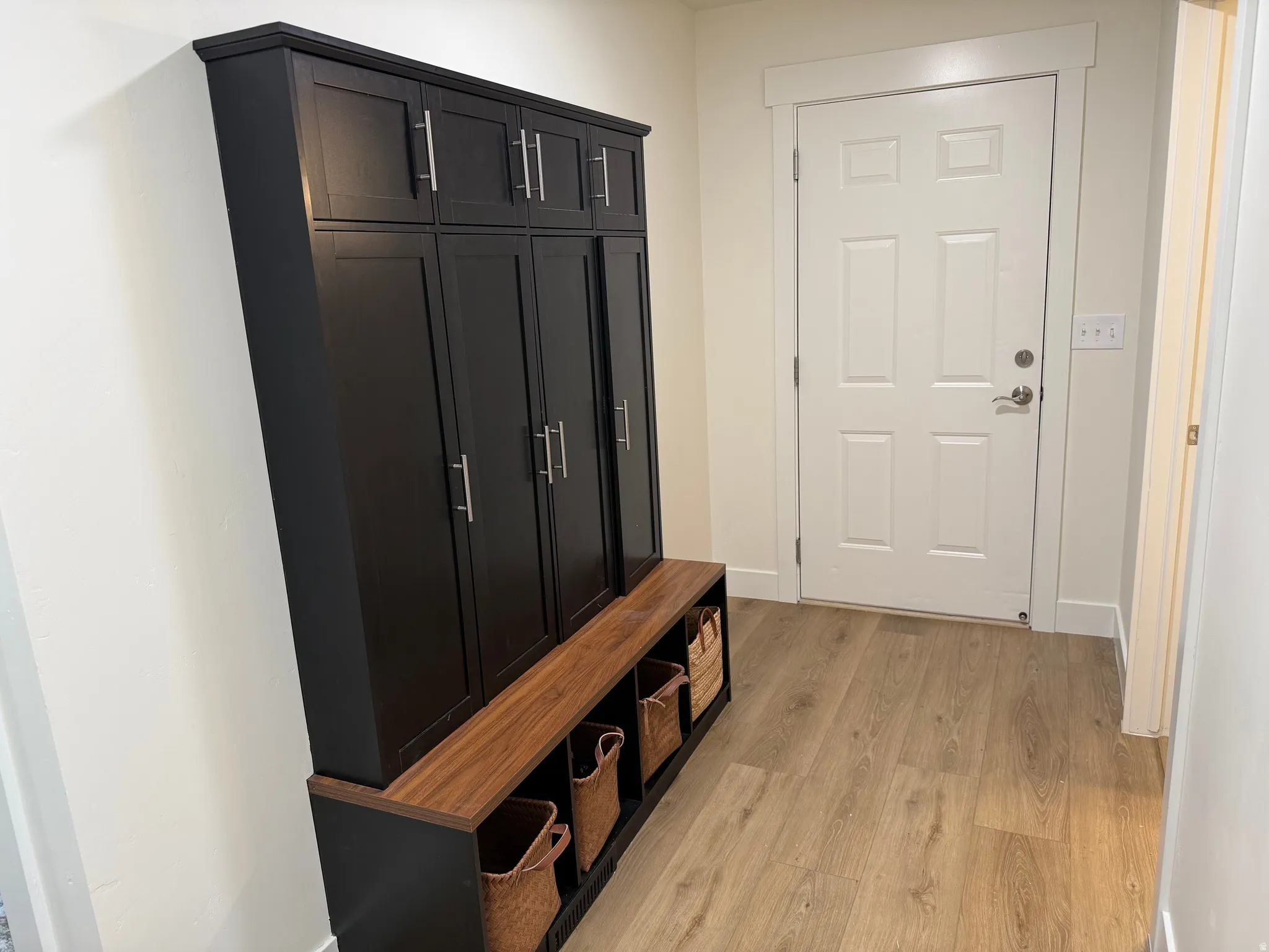 Entryway featuring a built-in storage unit with black cabinetry and a wood-finish bench with open shelving