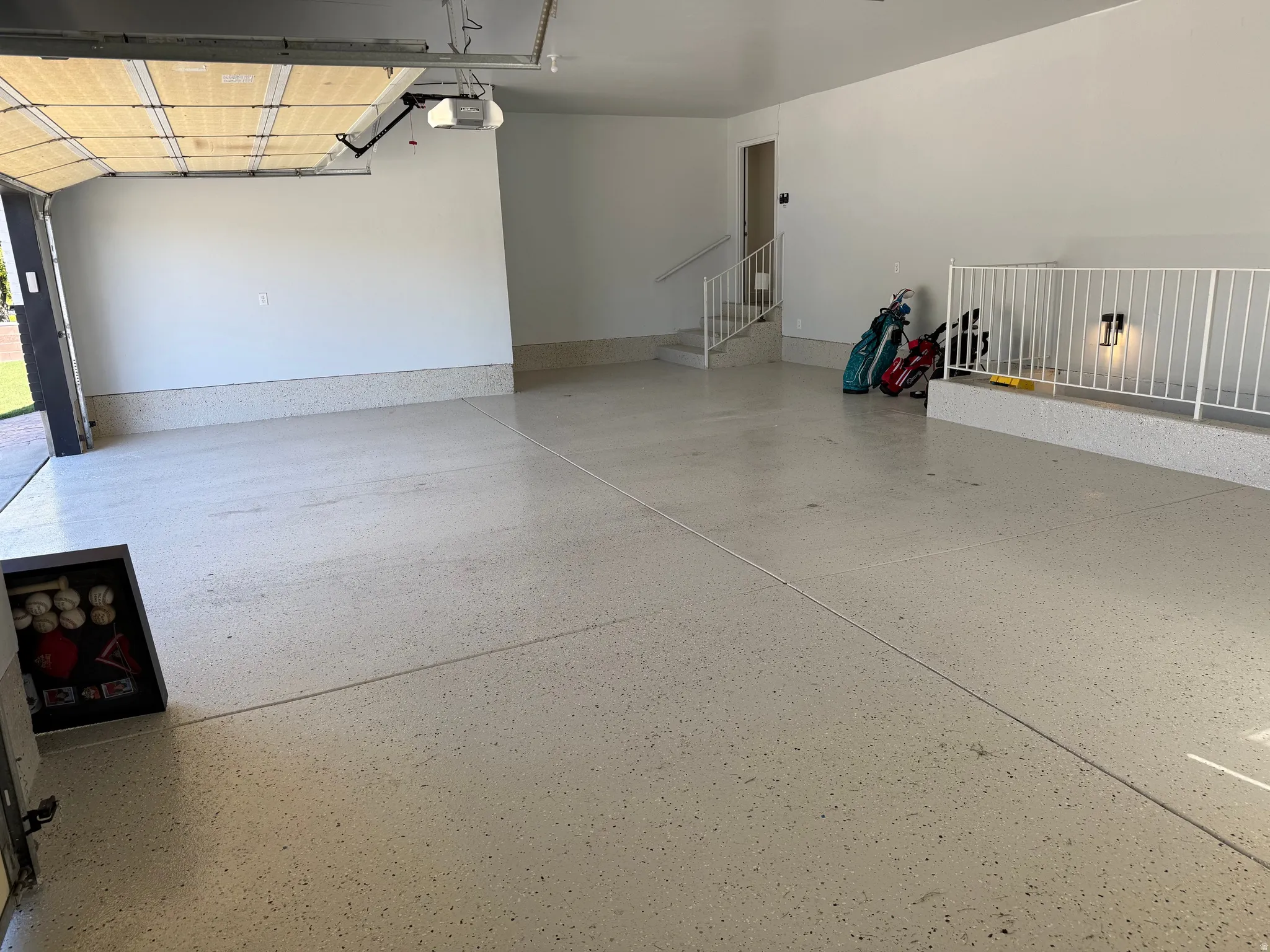 Spacious oversized 3 car garage with an epoxy-coated concrete floor, white painted walls, and an automatic garage door opener