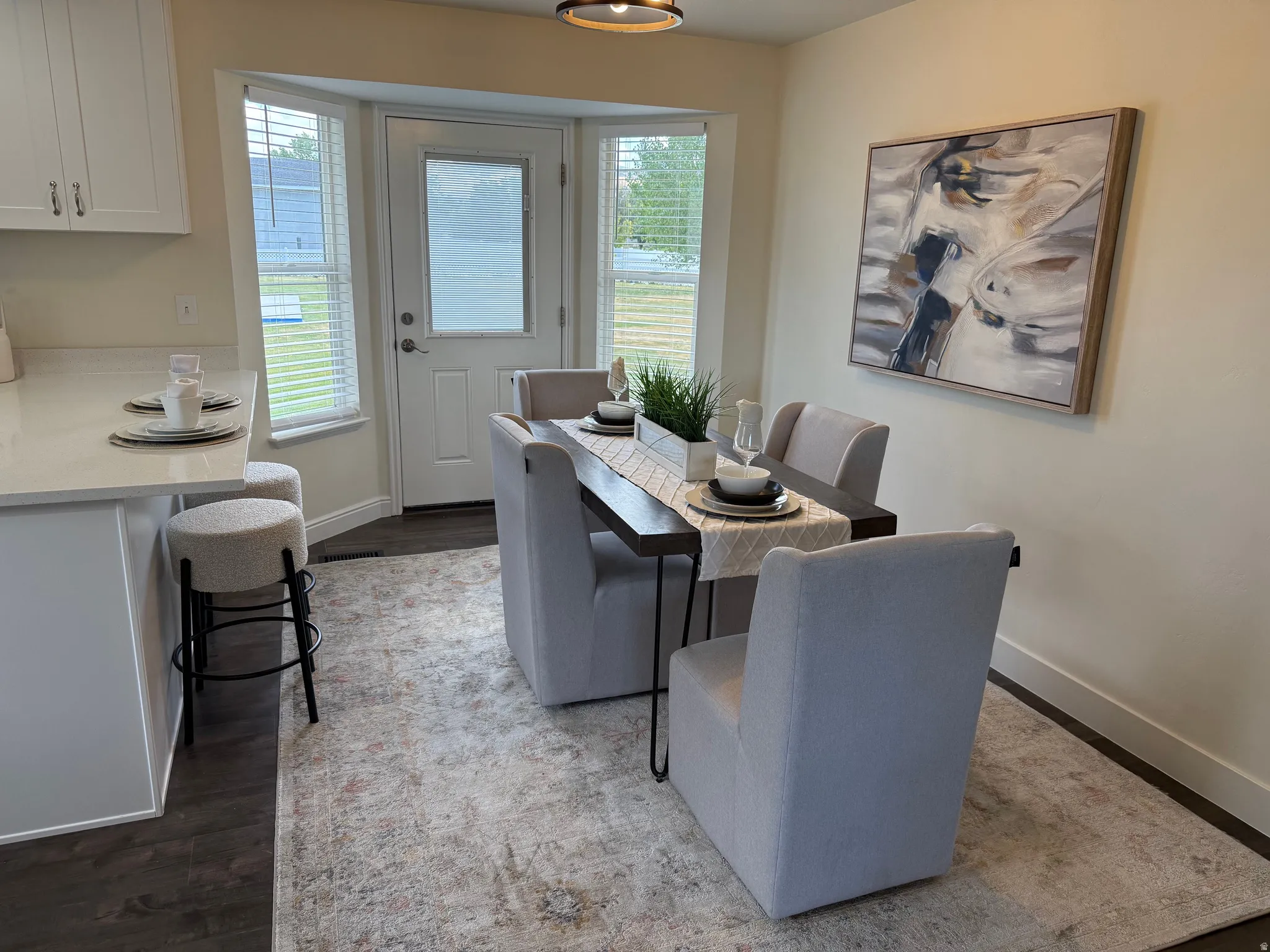 Dining area with wood-finish flooring and a bay window featuring blinds