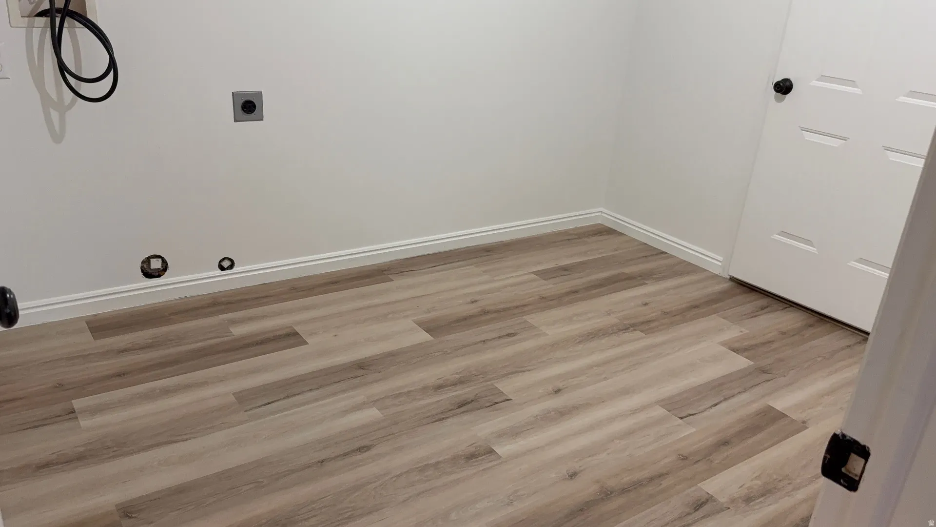 Light wood-finish flooring with white baseboards throughout