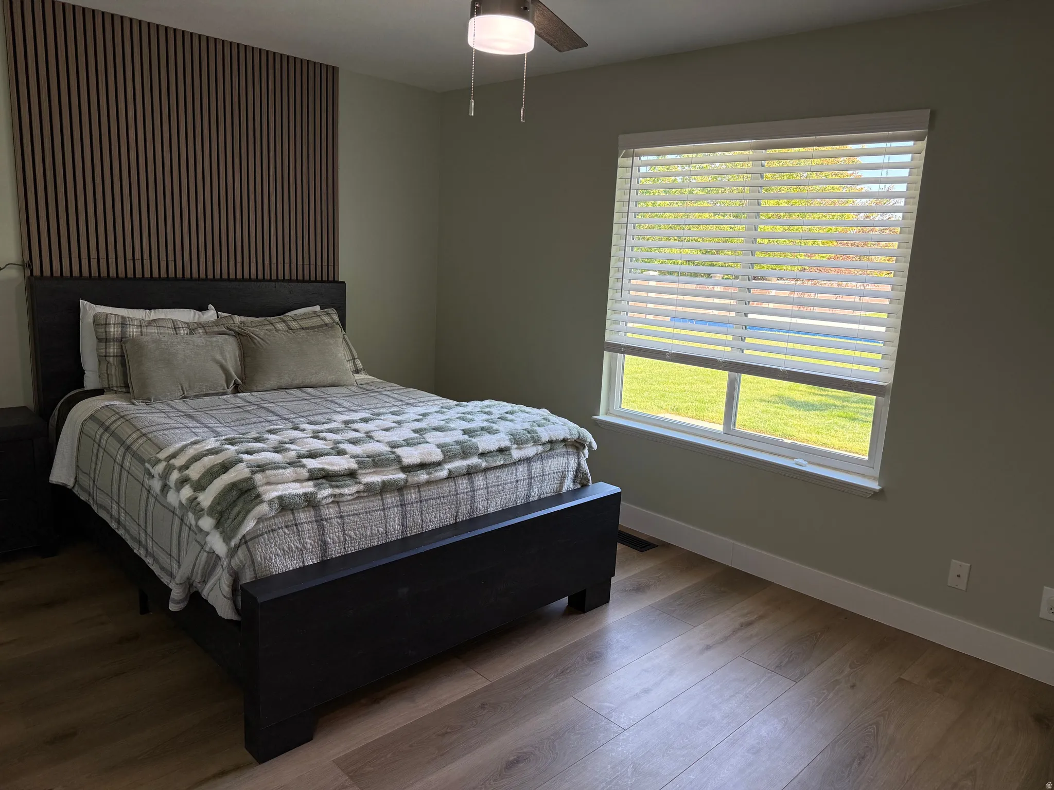 Bedroom featuring a wood-slat accent wall and wood-finish flooring