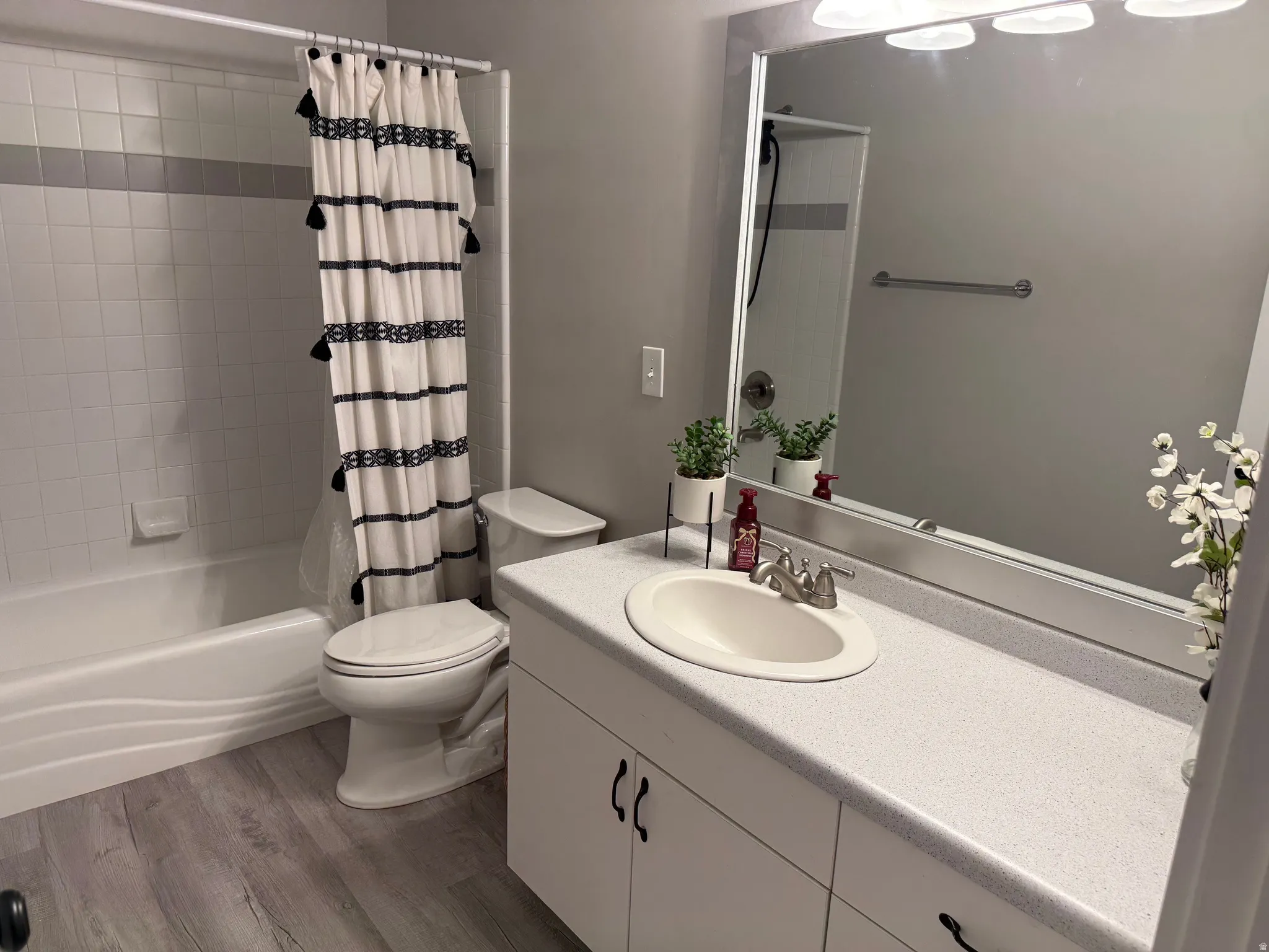Bathroom featuring a white vanity with integrated sink, a large wall-mounted mirror, and a full bathtub with tile surround