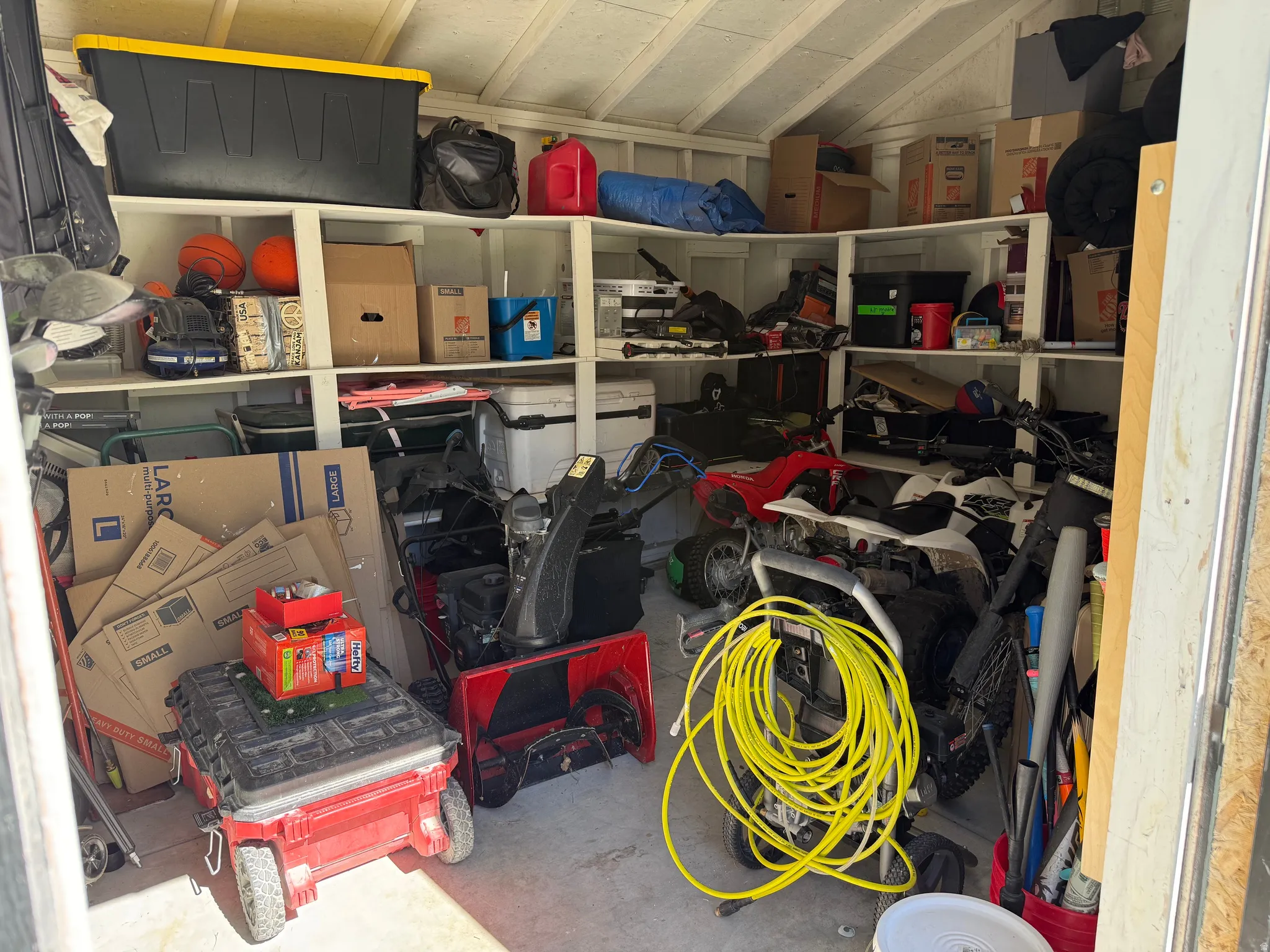 Storage shed interior featuring built-in shelving, a sloped ceiling, and a concrete floor