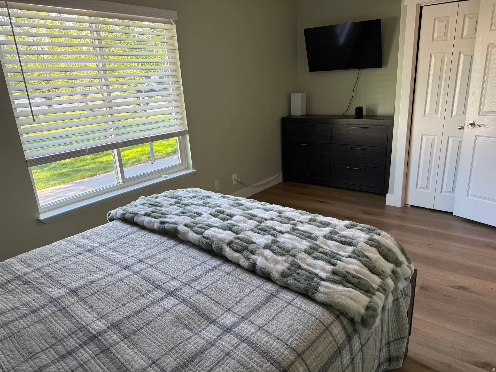 Room featuring wood-finish flooring, a double window with blinds, and light green walls