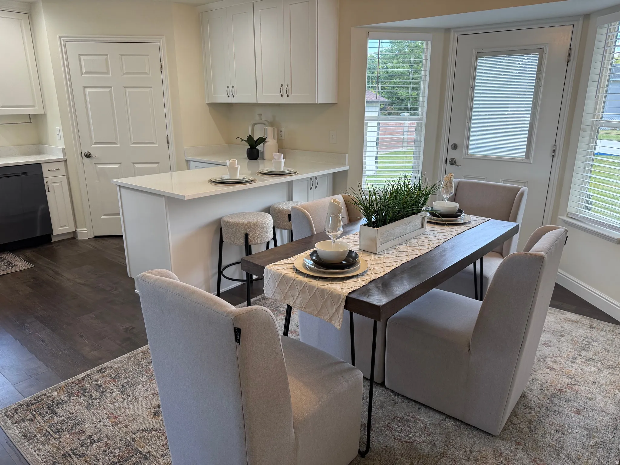 Kitchen and dining area featuring white cabinetry, light-toned countertops, and wood-finish flooring