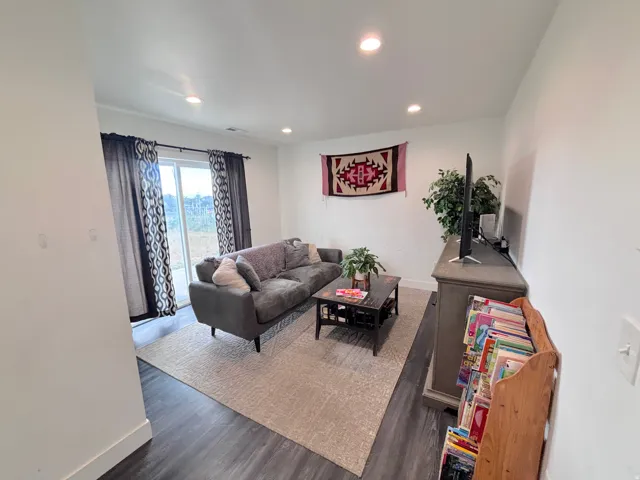 Bright living area featuring recessed lighting, dark wood-finish flooring, and a sliding glass door
