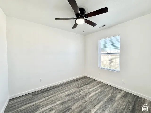 Wood-finish flooring with crisp white walls, a ceiling fan with integrated lighting, and a window with blinds