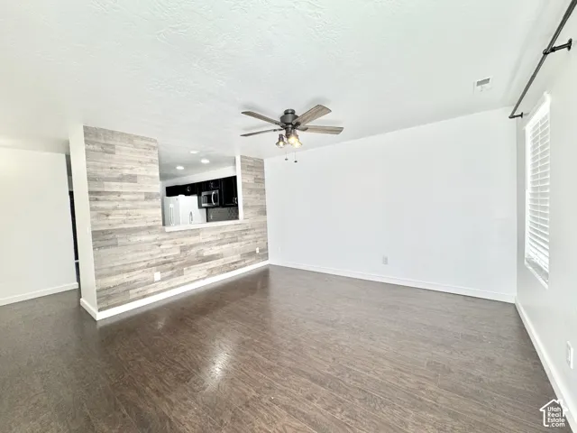 Spacious living area featuring wood-finish flooring, a ceiling fan, and white walls