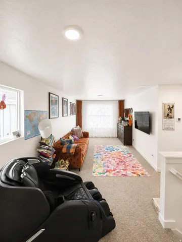 Carpeted living space featuring white walls and a large window with natural light