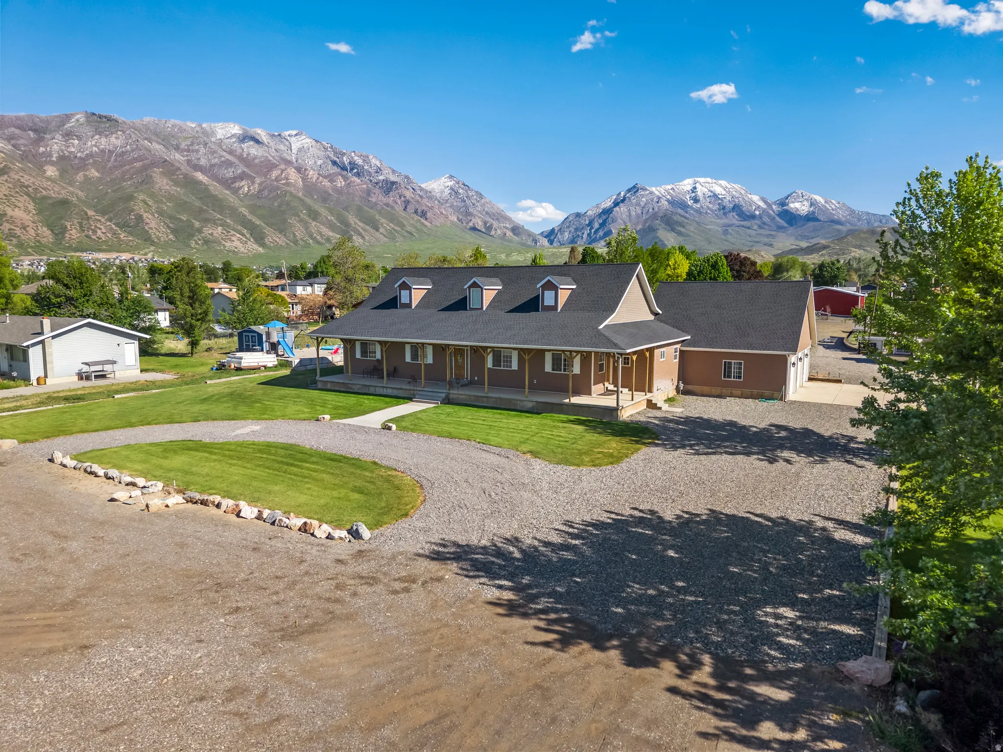Ranch-style residence featuring a covered front porch, dormer windows, and an attached two-car garage