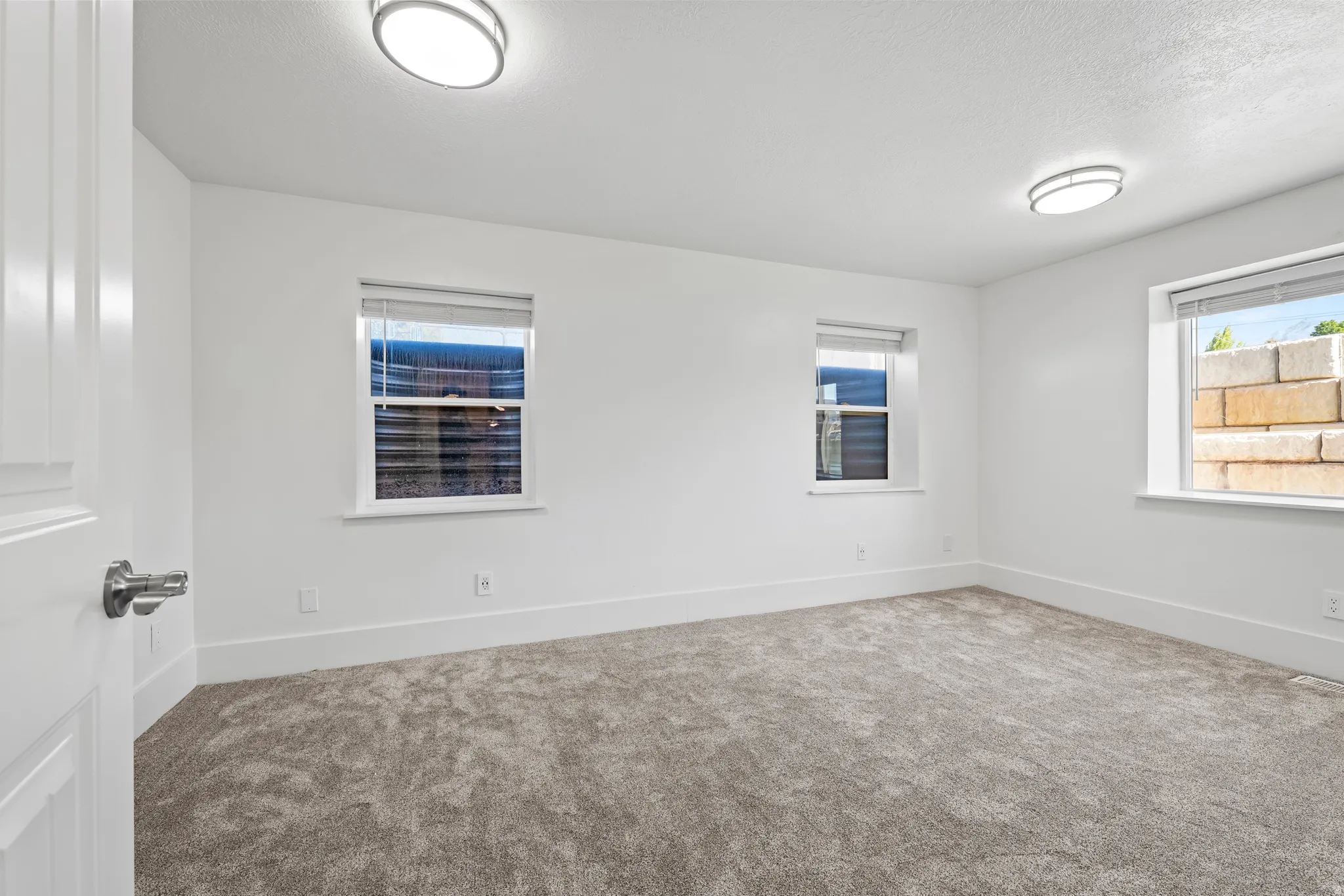 Bright interior space featuring light gray carpet flooring, white walls, and contemporary flush-mount ceiling lights