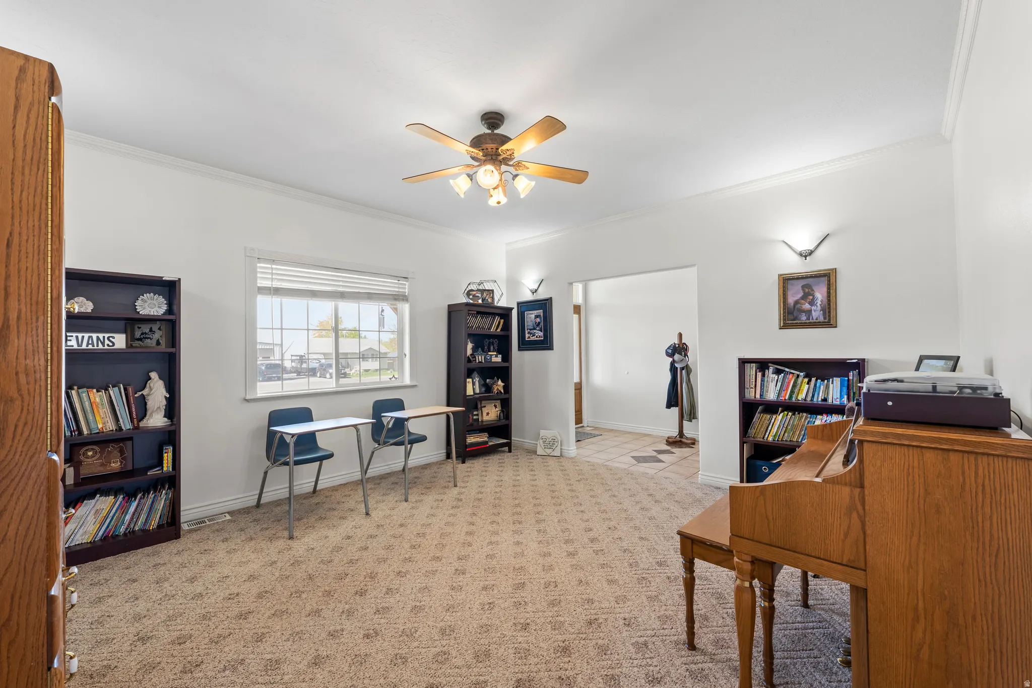 Spacious room featuring neutral patterned carpet, crown molding, and a ceiling fan with integrated lighting