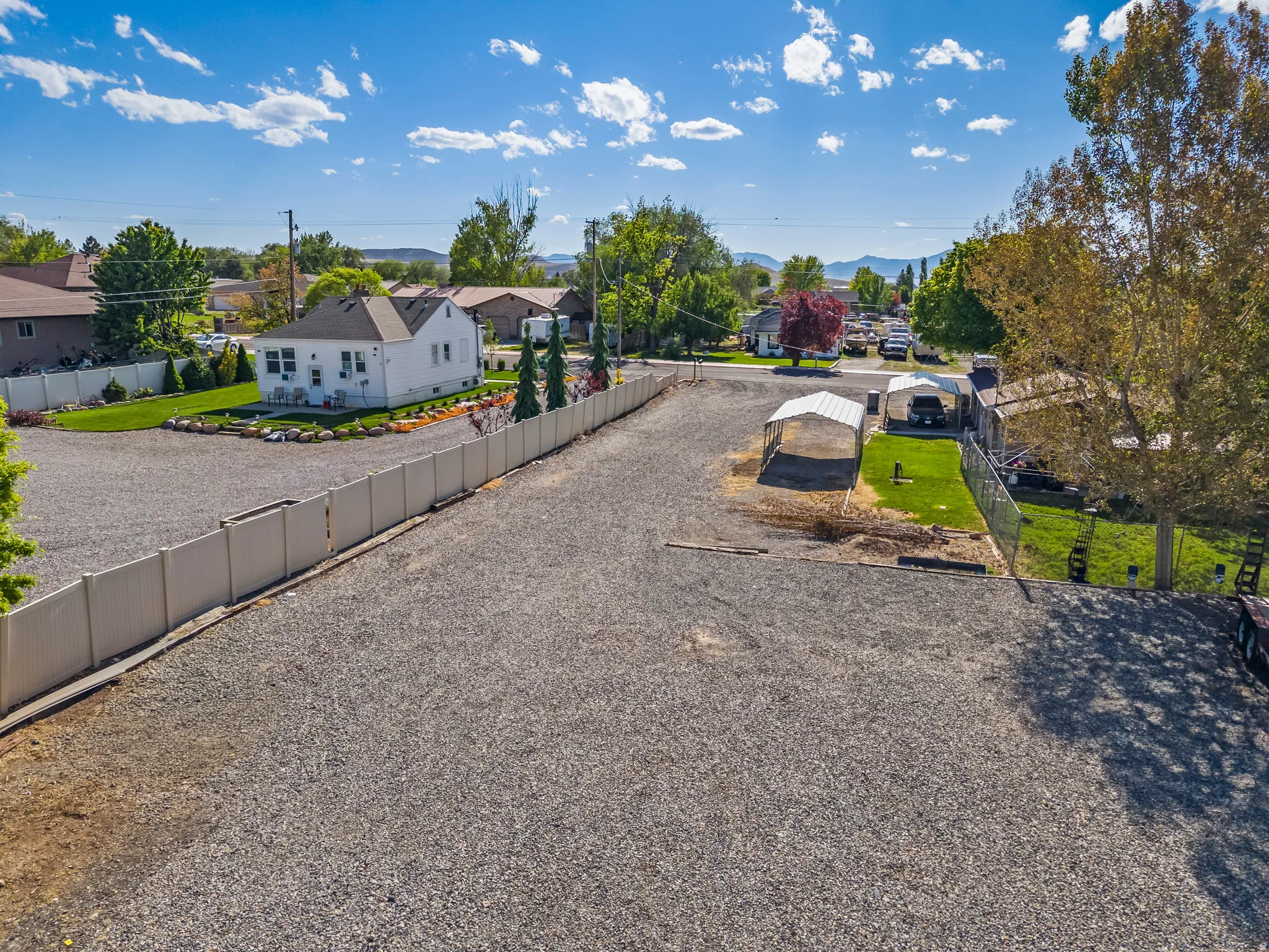 Expansive gravel lot featuring a white privacy fence