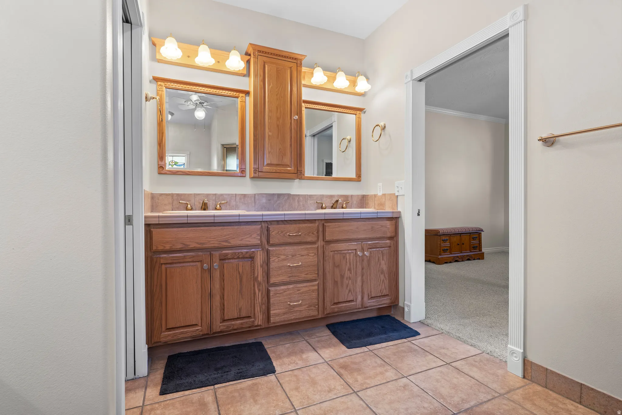 Double vanity with light wood cabinetry and a tile countertop