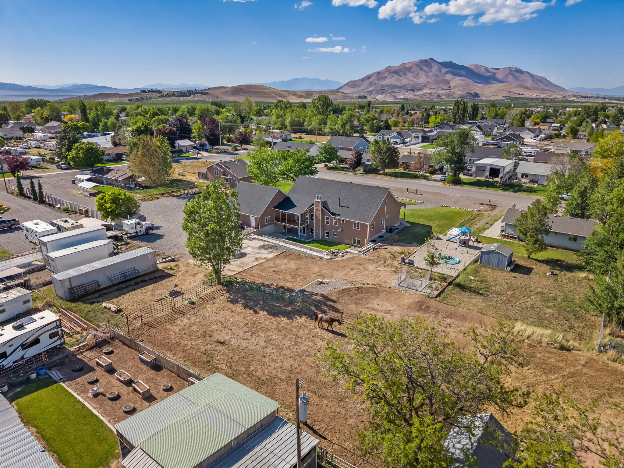 Expansive property featuring a large residence, surrounding grounds, mountain backdrop, and additional outbuildings