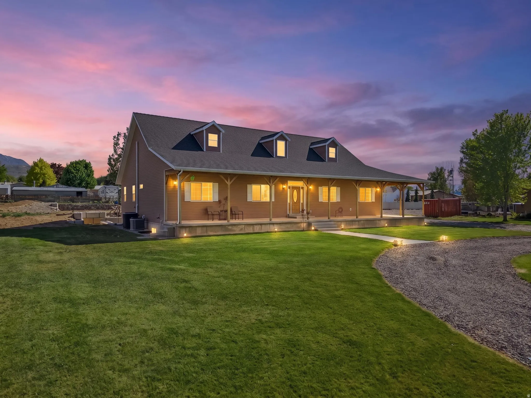 Spacious residence featuring a covered porch, dormer windows, and a manicured lawn