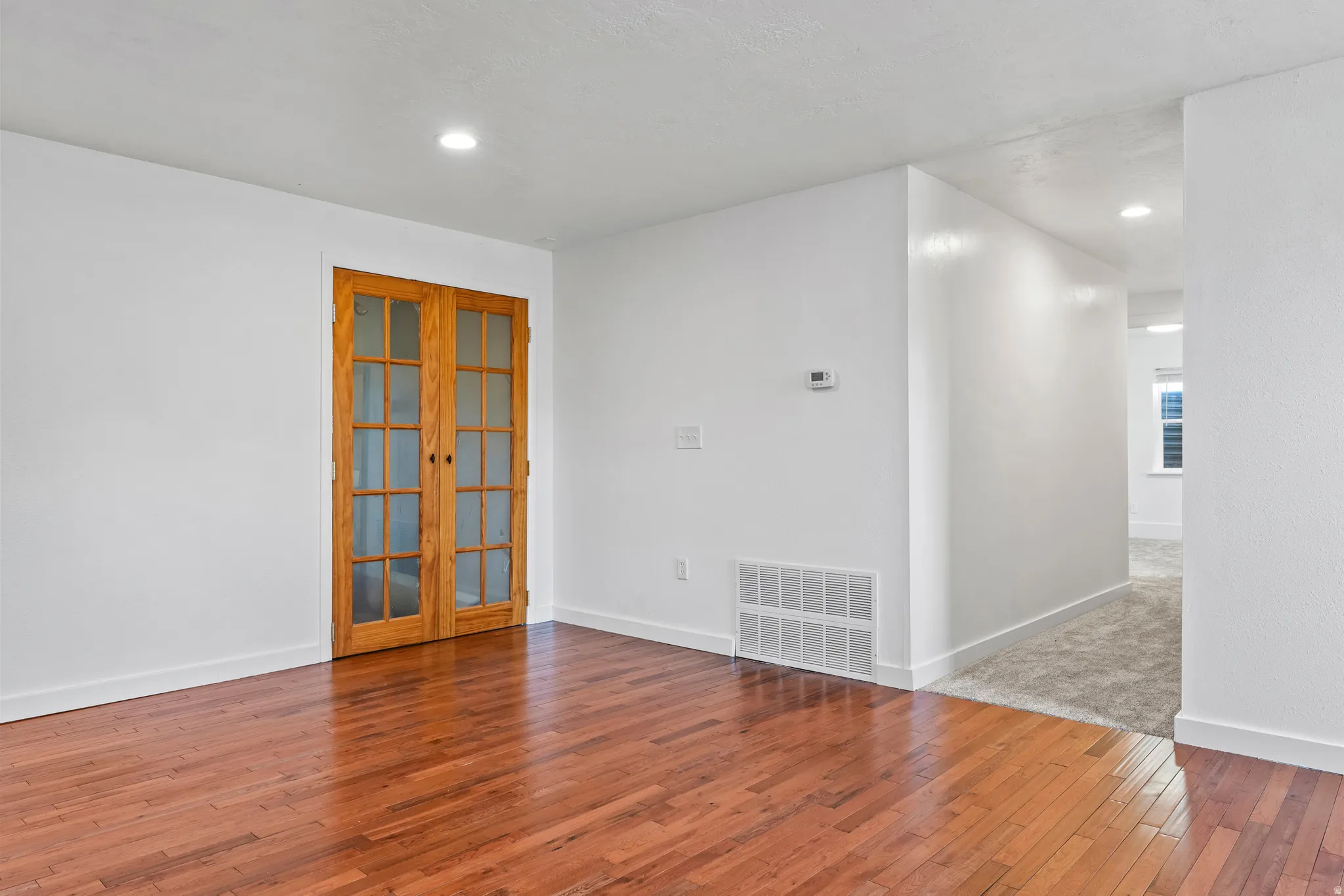 Warm wood-finish flooring complements crisp white walls in this interior space