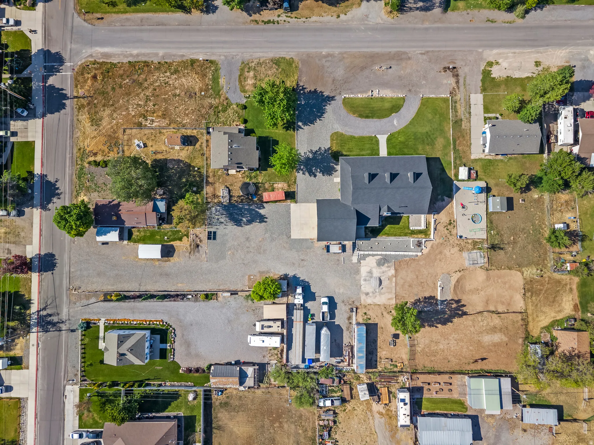 Aerial perspective showcasing a property with a main residence, an expansive gravel parking area, and a circular driveway