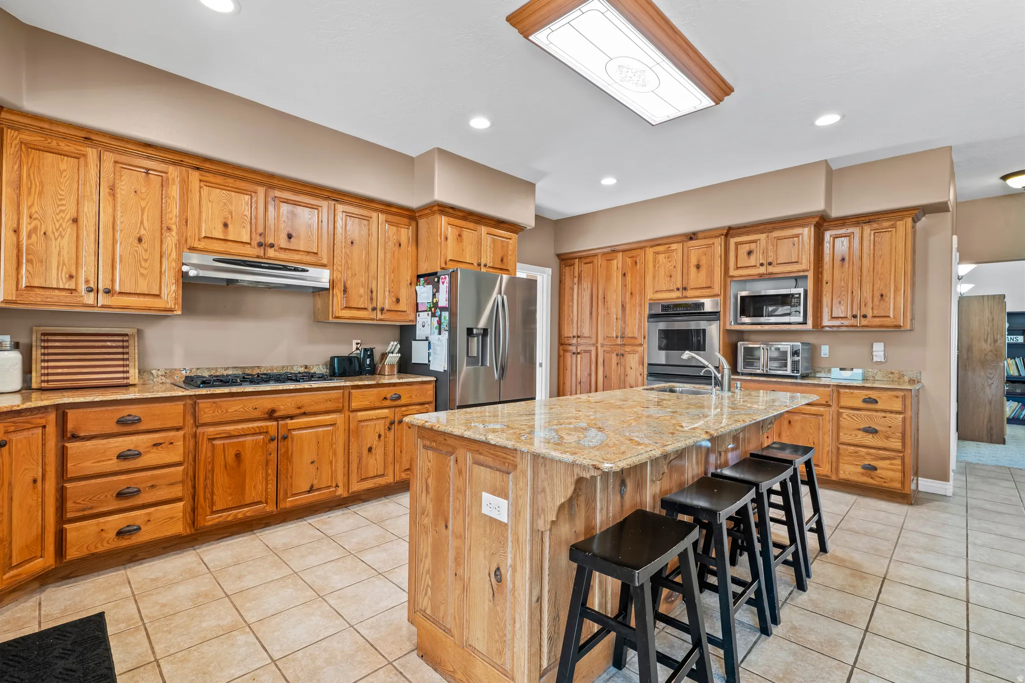 Expansive kitchen featuring wood cabinetry, granite countertops, and a central island with seating
