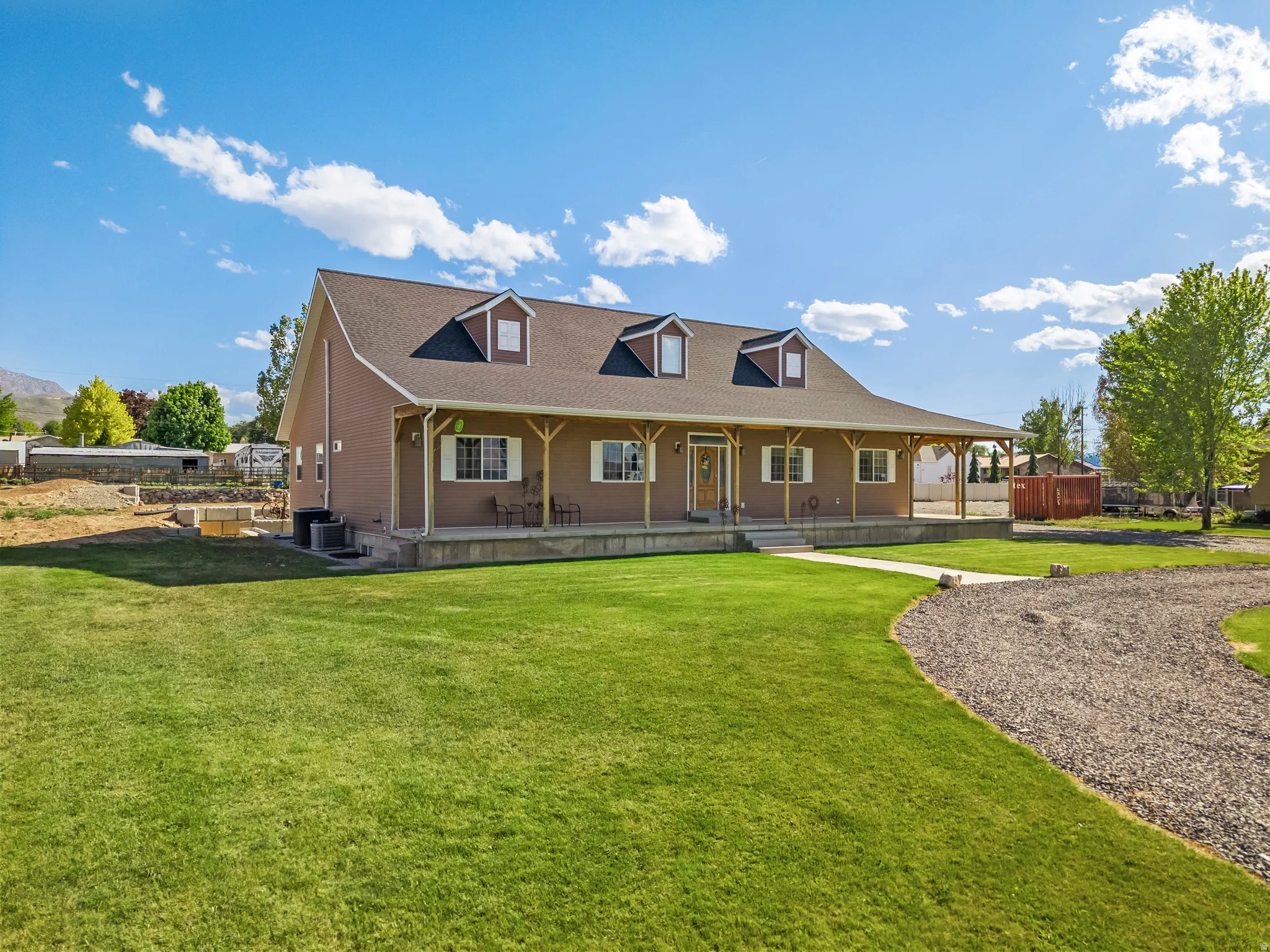 Traditional style home featuring a covered front porch, dormer windows, and a manicured front lawn