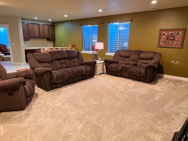 Spacious room featuring light-colored carpet, recessed ceiling lighting, and a built-in wet bar with wood cabinetry