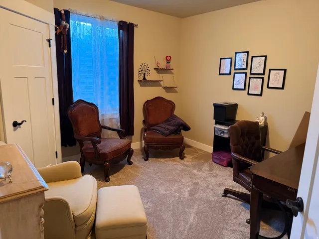 Carpeted room featuring a window with privacy sheers and dark curtains, a solid white door with black hardware, and neutral-toned walls