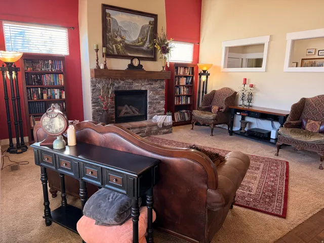 Living area featuring a floor-to-ceiling stone fireplace with a substantial wood mantel, integrated gas insert, and built-in shelving