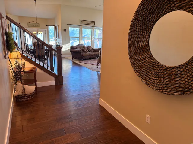 Spacious entryway featuring wood-finish flooring, a staircase with dark wood newel posts and wrought iron balusters, and light-toned walls with white baseboards