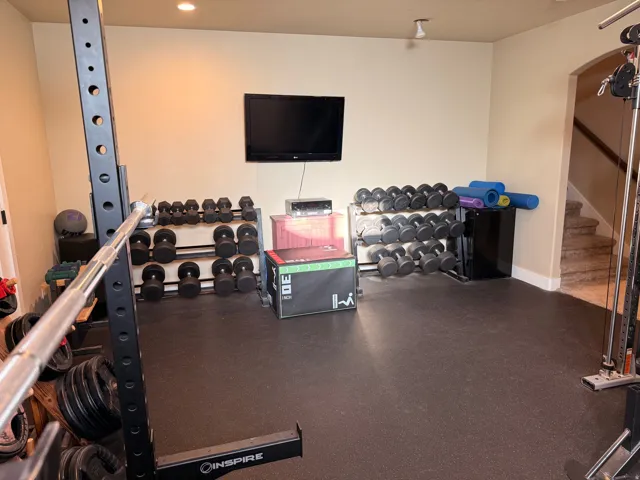 Dedicated fitness space featuring rubber flooring, recessed ceiling lighting, and a wall-mounted television