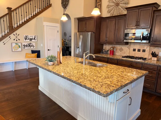 Kitchen island featuring a granite countertop, undermount sink, and white beadboard paneling