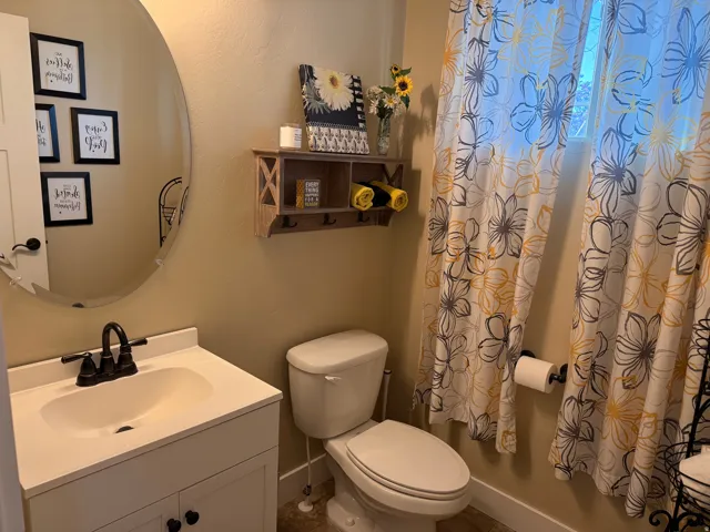 Bathroom featuring a white vanity with integrated sink, black-finish faucet, and an oval mirror