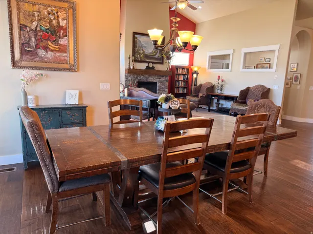 Spacious dining area featuring rich wood-finish flooring, a large rectangular dining table, and direct sightlines into an expansive living space