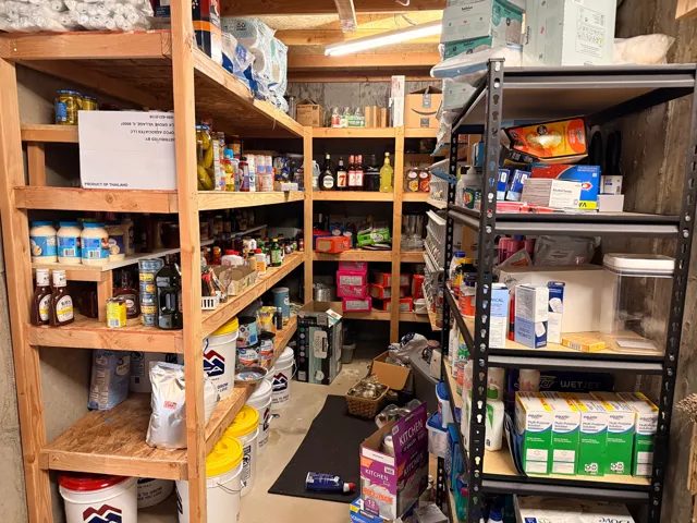 Dedicated storage room featuring extensive wooden shelving and black metal shelving units