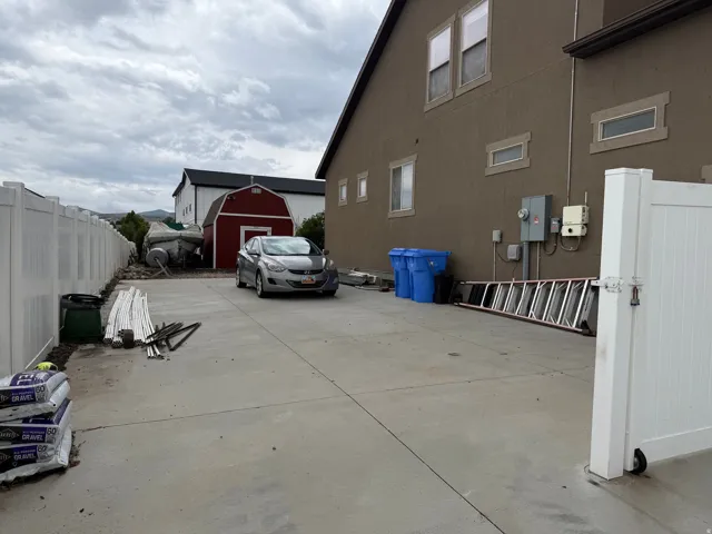 Spacious RV parking featuring a durable vinyl fence and a barn-style outbuilding