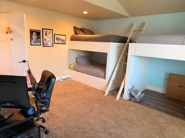 Spacious room featuring two built-in bunk bed structures with integrated ladders, recessed lighting, and a neutral-toned carpet throughout the majority of the floor