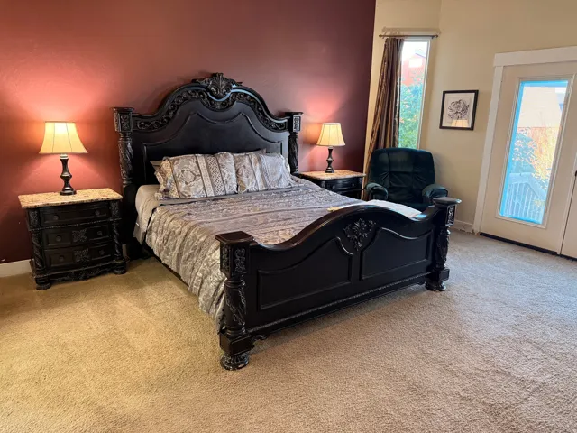 Master bedroom space featuring a single-panel patio door, a tall vertical window with drapery, and a rich accent wall