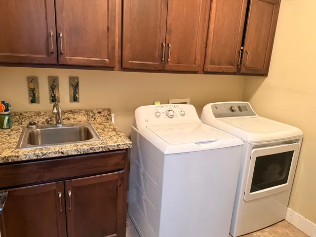 Dedicated utility area featuring a built-in sink with a stainless steel basin, a speckled granite-style countertop, and rich wood cabinetry with brushed nickel hardware