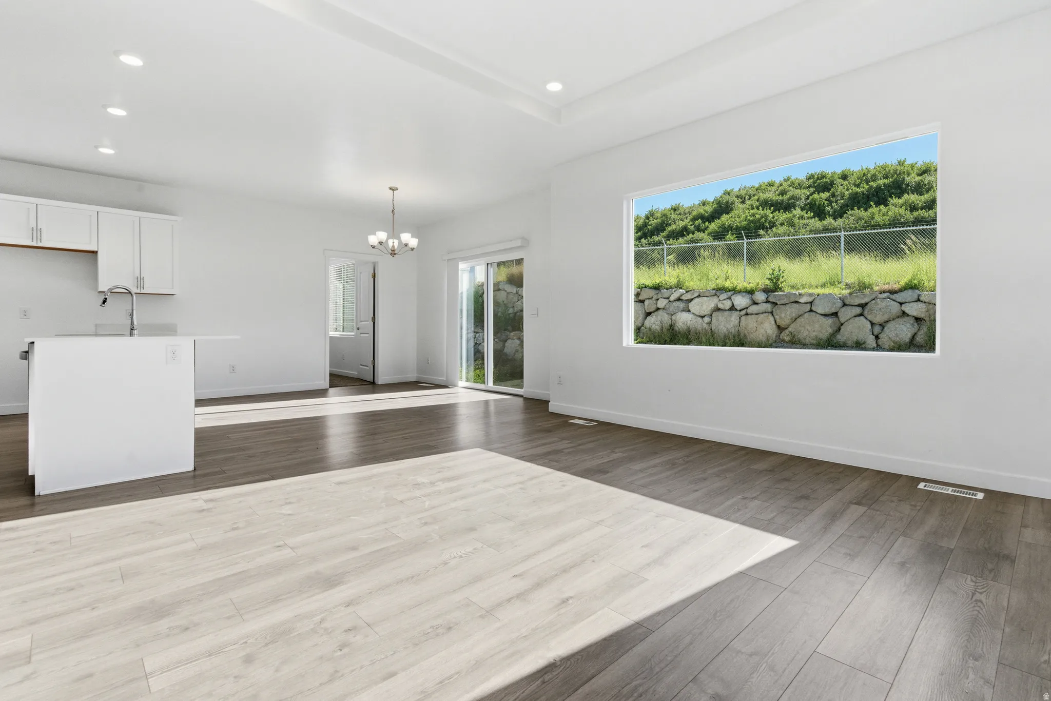 Open-concept living space featuring wood-finish flooring, recessed lighting, and a large picture window
