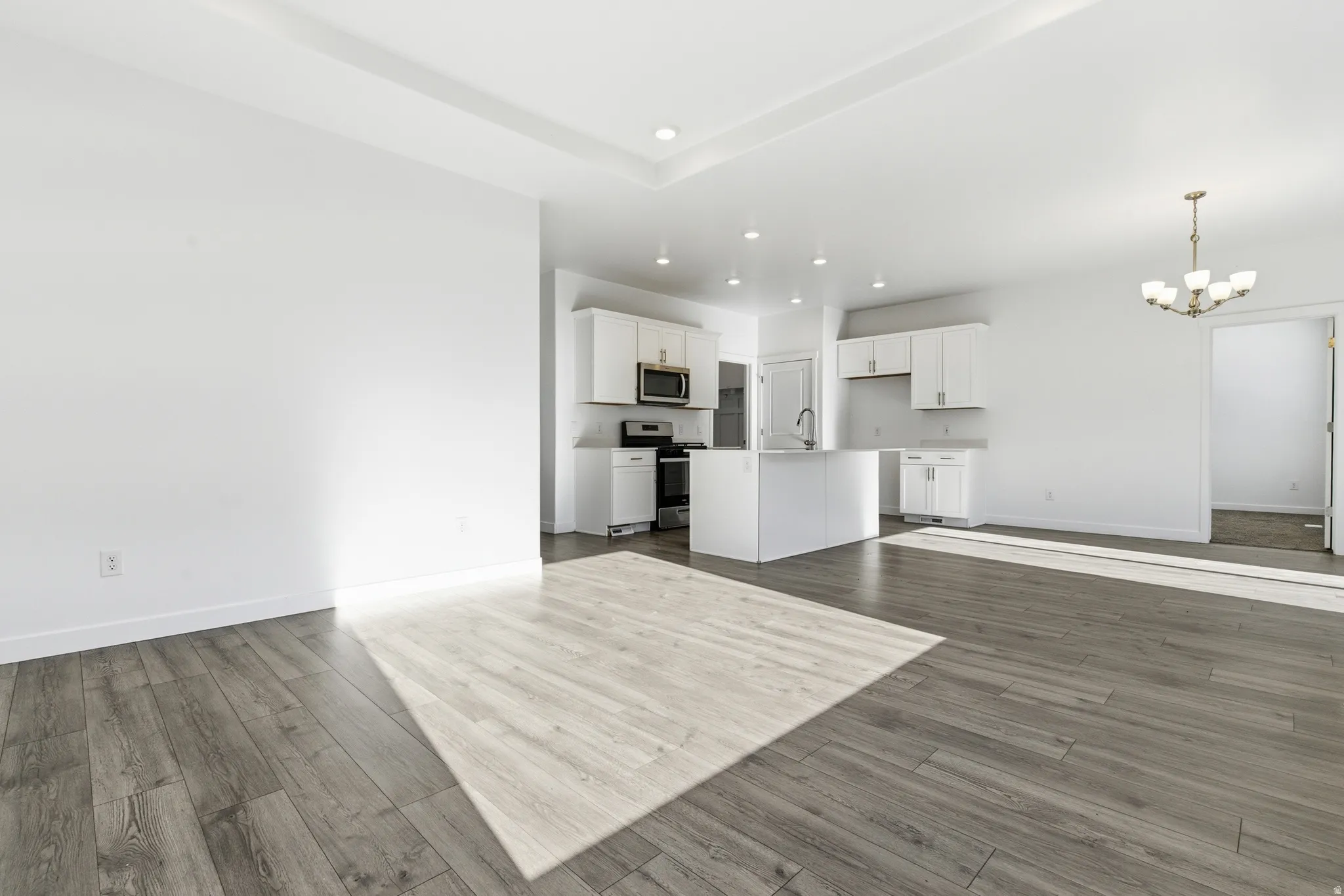 Spacious interior featuring wide plank wood-finish flooring, recessed lighting, and a tray ceiling