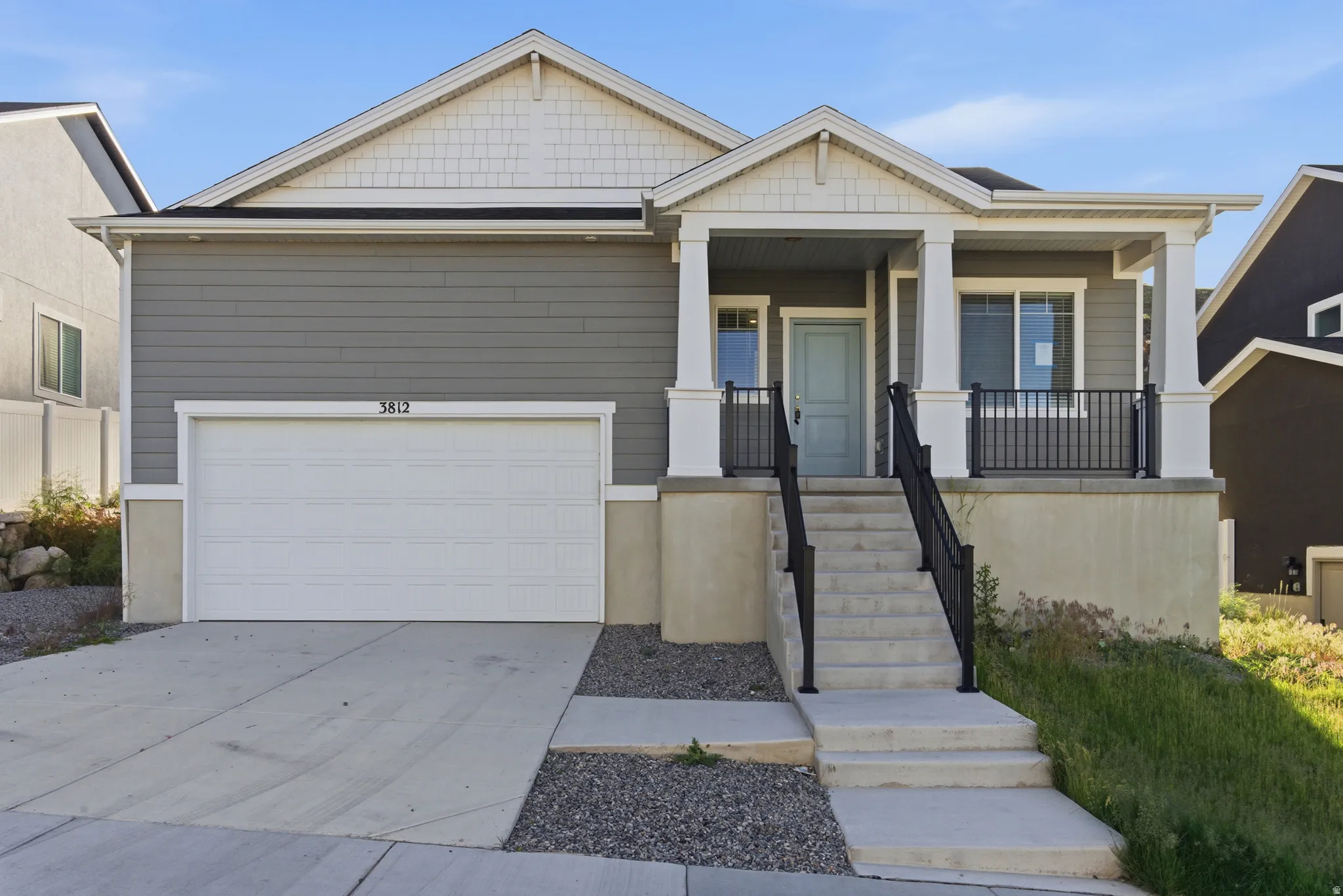 Gray siding exterior with white trim details and a covered front porch featuring white columns and black railings