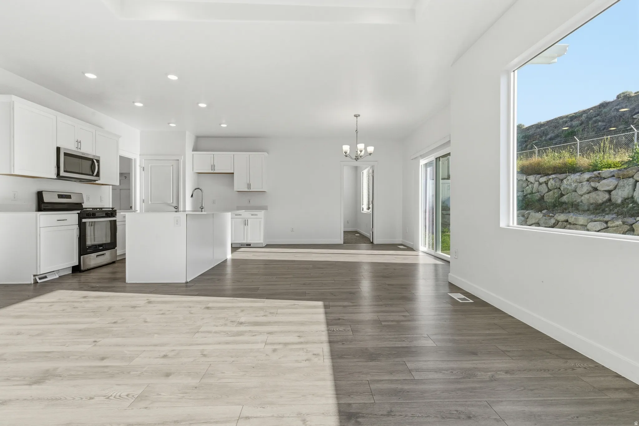 Open-concept living space with wood-finish flooring, recessed lighting, and a tray ceiling